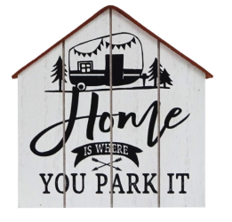 A white wooden sign in the shape of a house with a trailer and text saying "Home is where you park it"
